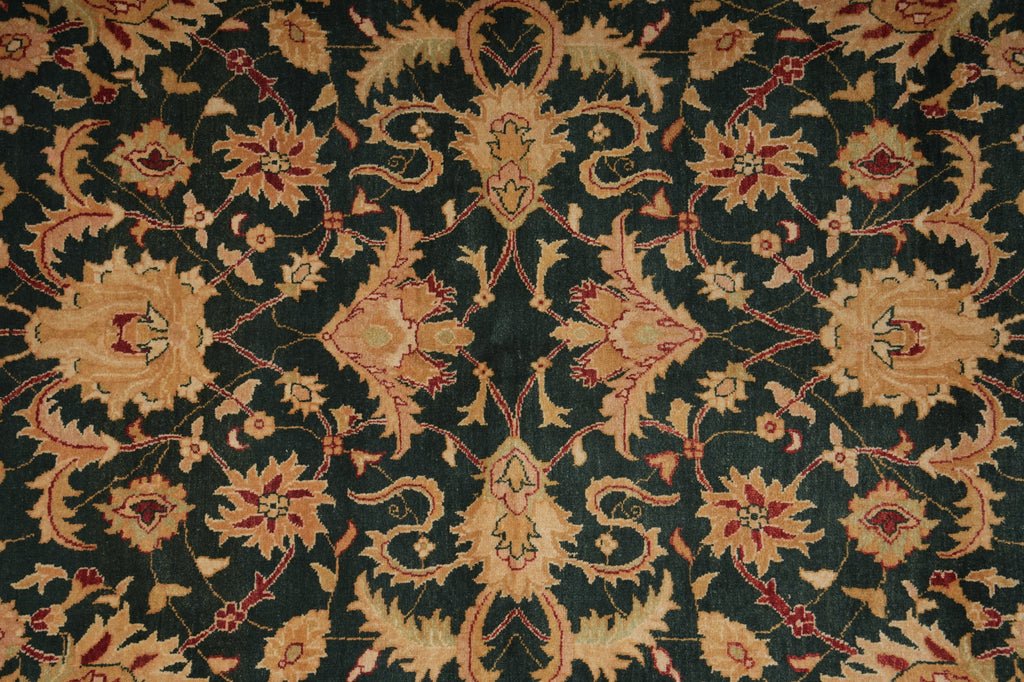 A close-up of an ornate damask patterned fabric with a dark green background and beige, gold, and red floral motifs.
