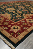 Load image into Gallery viewer, A close-up of a traditional patterned area rug showing its corner detail, featuring a dark green field, a deep red border, and cream floral motifs.