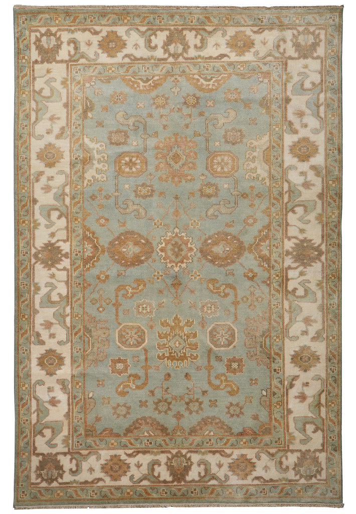 A traditional rectangular area rug with an ornate central medallion and floral motifs, featuring a light blue field, beige and cream borders, and muted rust-brown accents.