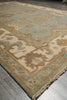Load image into Gallery viewer, A close-up of a traditional patterned area rug with a light blue-green field, beige borders, and cream central motifs, shown on a gray tiled floor.