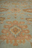 Load image into Gallery viewer, A close-up of a patterned rug or textile with a muted sage green background and large peach, tan, and beige floral or medallion motifs.