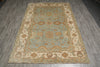 Load image into Gallery viewer, A rectangular traditional area rug with an ornate floral and medallion pattern, featuring a light blue center field and cream borders, laid out on a gray wood-look floor.