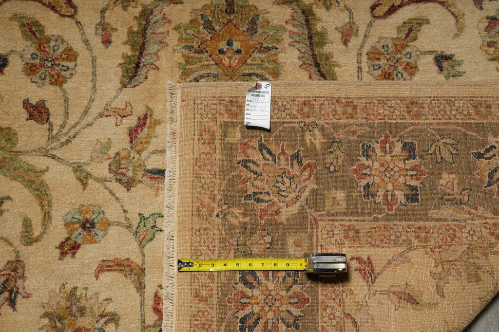 A close-up of a patterned area rug with a beige base and multicolor floral motifs, shown with a yellow tape measure and a product tag to indicate size.