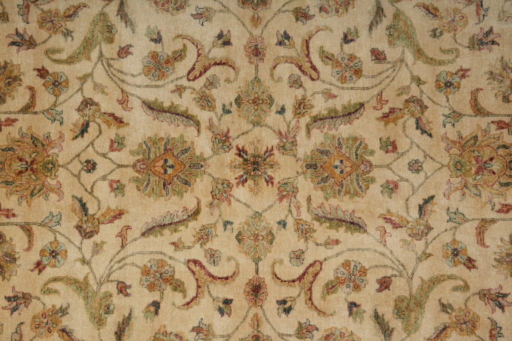 A close-up of an ornate floral patterned rug or textile in warm beige, with cream, muted green, rust red, and brown detailing.