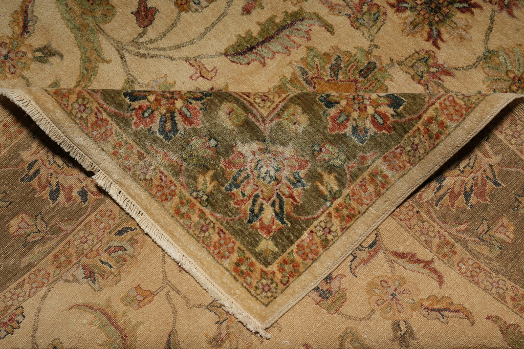 A close-up of a traditional oriental-style rug corner, showing a beige and olive green base with floral motifs in muted red, blue, and brown tones, with a fringed edge visible.