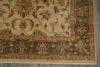 Load image into Gallery viewer, A close-up of a traditional oriental rug showing its corner, featuring a beige central field with floral motifs and a dark olive green border with red and blue accents.