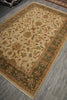 Load image into Gallery viewer, An ornate rectangular area rug with a beige center and detailed floral motifs, bordered in green, rust, and cream, shown on a gray tiled floor.
