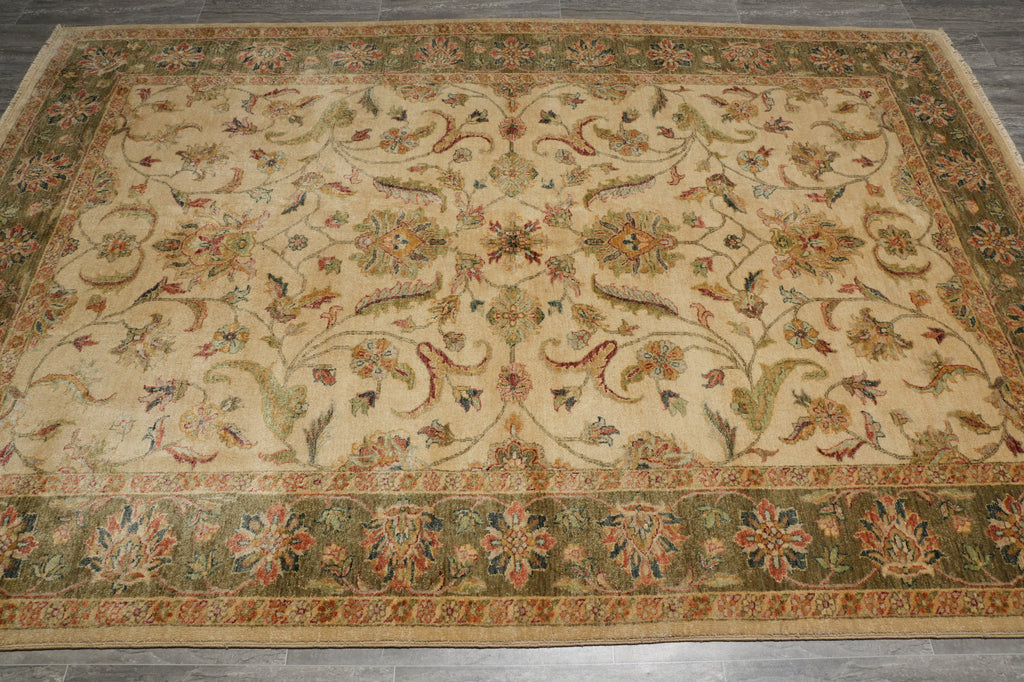 An antique-style oriental area rug with a beige center field and a green border, featuring intricate floral and scrolling vine patterns in muted red, blue, and green tones.