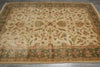 Load image into Gallery viewer, An antique-style oriental area rug with a beige center field and a green border, featuring intricate floral and scrolling vine patterns in muted red, blue, and green tones.