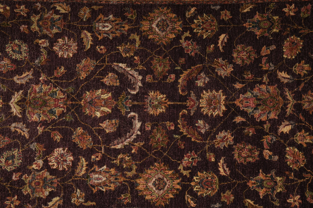 A close-up of an ornate traditional rug with a dark brown background and intricate floral motifs in beige, rust, and muted gold.