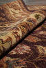 Load image into Gallery viewer, A close-up of a folded area rug showing its detailed traditional pattern in shades of brown, beige, and muted red.