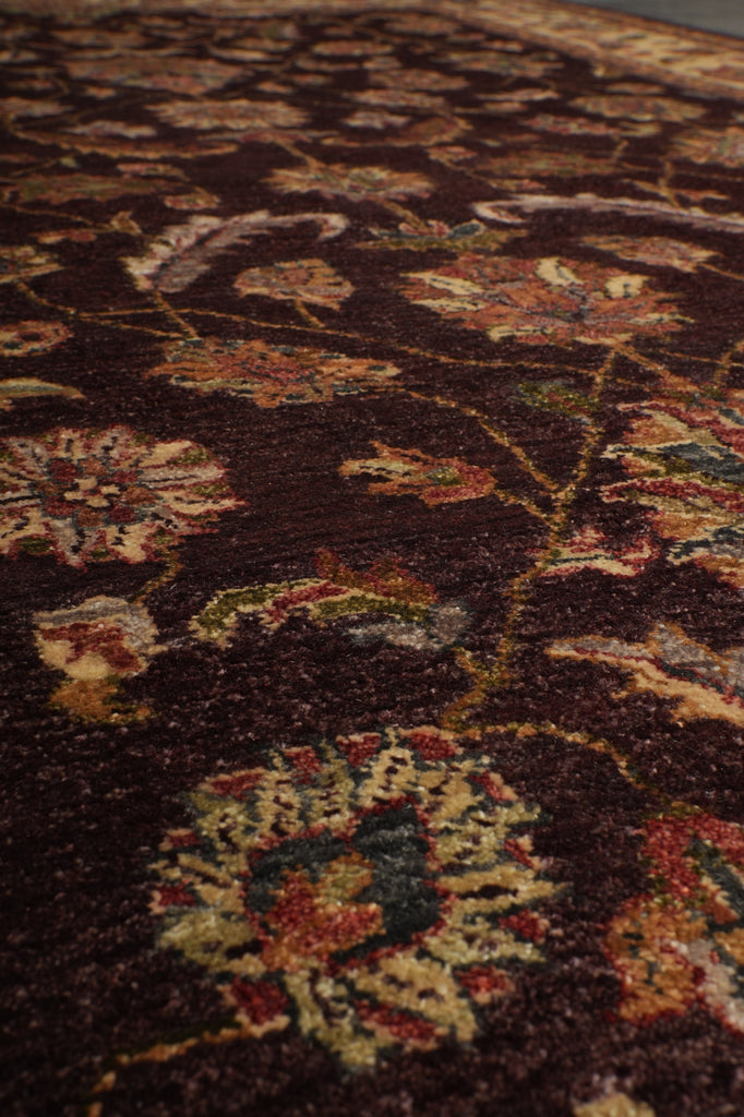 Close-up of an ornate floral patterned rug with a dark brown background and cream, red, and green details.