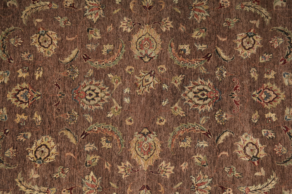 A close-up of a brown patterned rug or textile with an ornate floral and paisley design in beige, muted green, and small red accents.