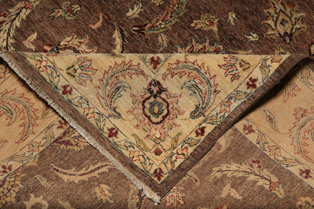 A close-up of an ornate area rug showing its detailed woven pattern, featuring a central cream-colored triangular medallion with floral motifs and fringed edges, surrounded by a brown and beige paisley design.
