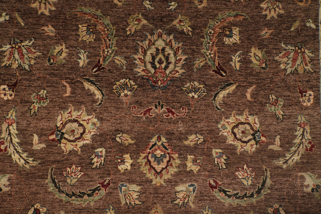 A close-up of a traditional patterned rug with a warm brown background and cream, beige, and muted red floral motifs.