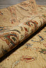 Load image into Gallery viewer, A close-up of a rolled area rug showing its detailed woven pattern in beige, rust red, and blue on a light tan background.