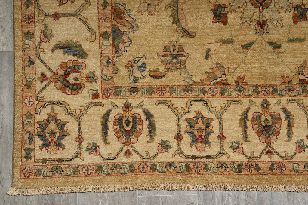 A close-up of an ornate area rug showing its detailed floral pattern and fringed edge, laid out on a gray tiled floor.