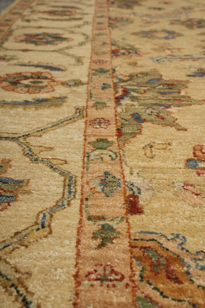 Close-up of an ornate area rug with a central patterned border and floral motifs in beige, rust, blue, green, and brown tones.