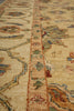 Load image into Gallery viewer, Close-up of an ornate area rug with a central patterned border and floral motifs in beige, rust, blue, green, and brown tones.