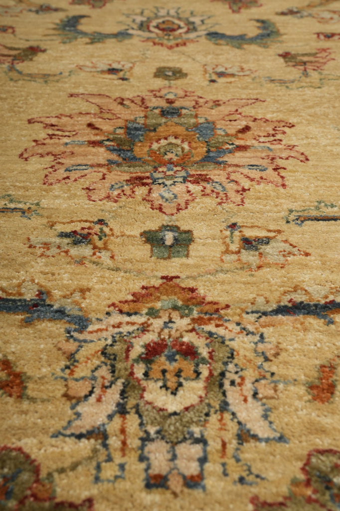 A close-up of a traditional patterned rug with a beige base and intricate floral motifs in red, blue, and brown.