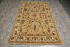 Load image into Gallery viewer, A rectangular vintage-style area rug with an ornate floral pattern, laid out on a gray wood-look floor. The rug features a warm beige base with brown, blue, and rust-red accents in its detailed motifs.