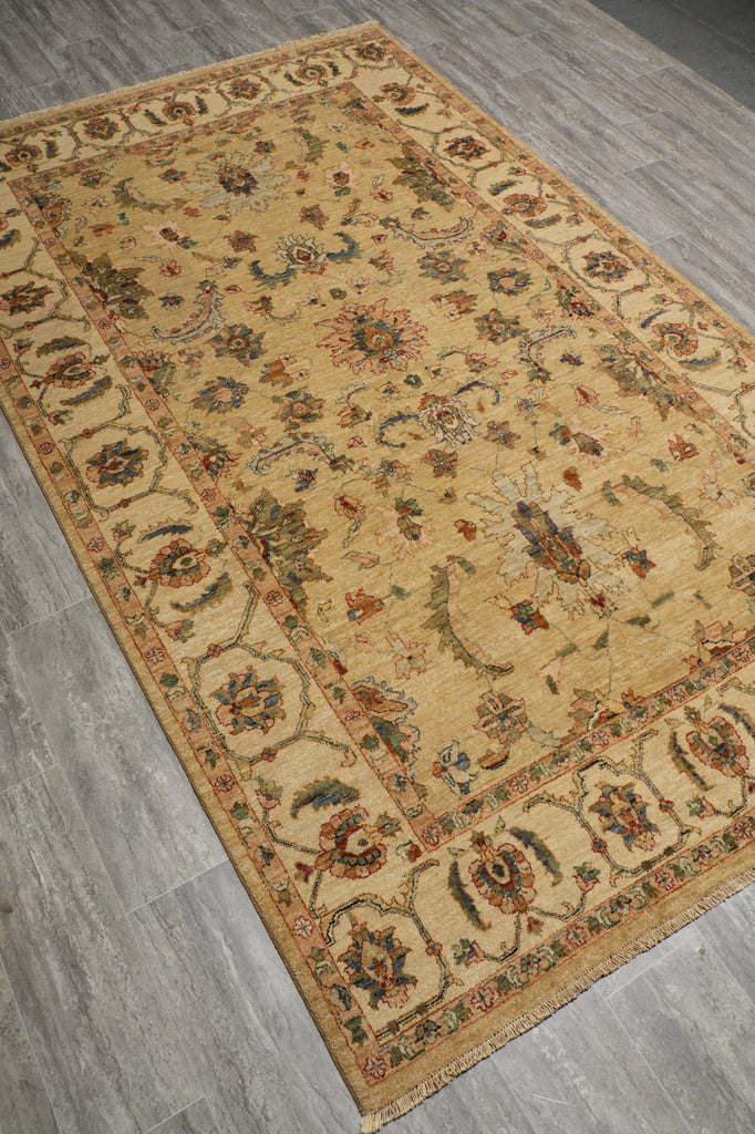 A rectangular area rug with an intricate traditional floral pattern, shown laid out on a gray wood-look floor.