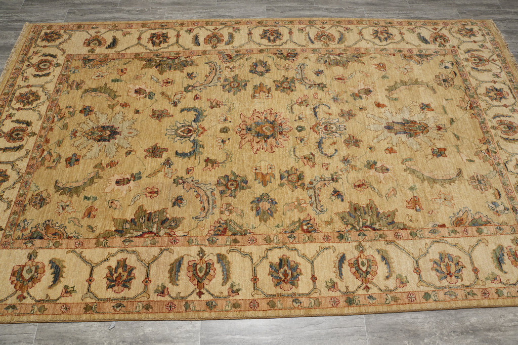 A rectangular vintage-style area rug with an ornate floral and medallion pattern, featuring a warm beige base with accents of rust red, blue, and green, laid out on a gray tiled floor.