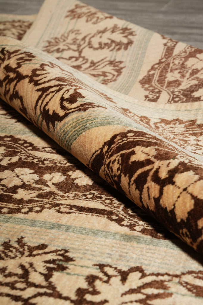 A close-up of a rolled area rug showing its detailed pattern. The rug features a complex design with dark brown motifs on a cream background, accented with light blue-green stripes.