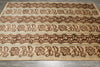 Load image into Gallery viewer, A rectangular area rug with a traditional floral and geometric pattern in dark brown on a natural beige jute background, laid flat on a gray tiled floor.