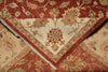 Load image into Gallery viewer, A close-up of a folded patterned rug showing its cream center with a red and green floral medallion, surrounded by a red border, laid over another view of the rug's beige and rust floral pattern.