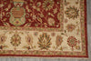 Load image into Gallery viewer, A close-up of a traditional patterned rug showing a deep red field with a large central medallion and a cream border decorated with floral motifs in red, green, and beige.