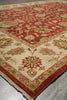 Load image into Gallery viewer, A close-up of an ornate area rug showing its corner, featuring a traditional floral and vine pattern in red, beige, and green.