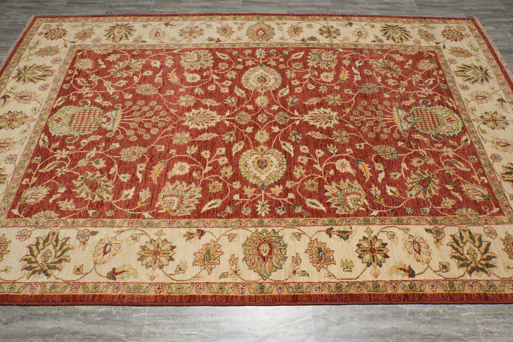 A traditional oriental area rug with an intricate floral pattern, featuring a deep red center field, a beige border, and accents of green, blue, and gold.
