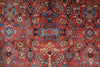 Load image into Gallery viewer, A close-up of a traditional patterned rug with a coral-red field, blue and beige floral motifs, and dark navy outlines.