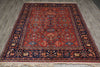 Load image into Gallery viewer, A traditional oriental area rug with a complex floral and geometric pattern, featuring a dominant red field, dark navy borders, and accents of beige and blue, laid out on a gray wood-look floor.