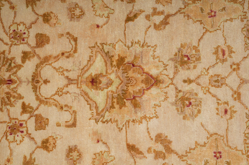 A close-up of a vintage-style floral patterned rug in beige and brown tones with subtle muted red accents.