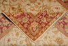 Load image into Gallery viewer, A close-up of a traditional oriental rug with a folded corner revealing its red, gold, and beige pattern, layered over a larger cream-colored rug with floral motifs.