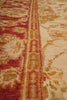 Load image into Gallery viewer, Close-up of an ornate area rug with a central vertical border featuring repeating medallion motifs in rust red, gold, and cream, with a floral field on the right side.