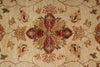Load image into Gallery viewer, Close-up of a woven rug with a central floral medallion in rust red, beige, ochre, and muted blue-green tones on a warm cream background.