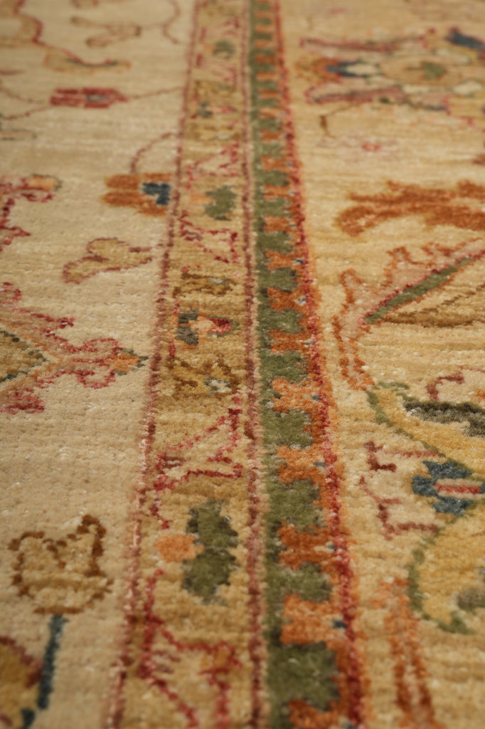 Close-up of a vintage patterned rug with a beige base and traditional motifs in muted red, green, and blue.