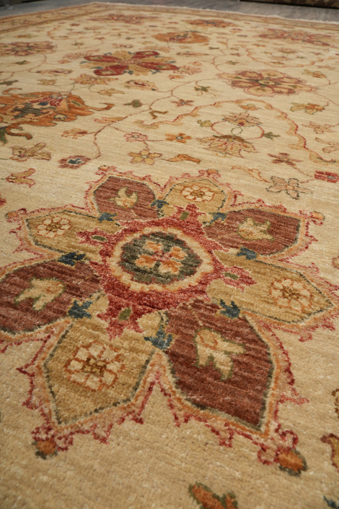 Close-up of an ornate traditional area rug with a large central floral medallion in beige, rust red, brown, and muted blue tones.