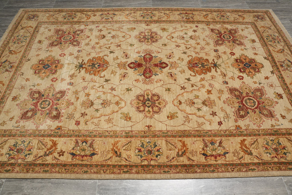 A rectangular area rug with an intricate traditional floral pattern in beige, rust, and brown tones, laid out on a gray tiled floor.