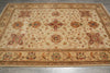 Load image into Gallery viewer, A rectangular area rug with an intricate traditional floral pattern in beige, rust, and brown tones, laid out on a gray tiled floor.