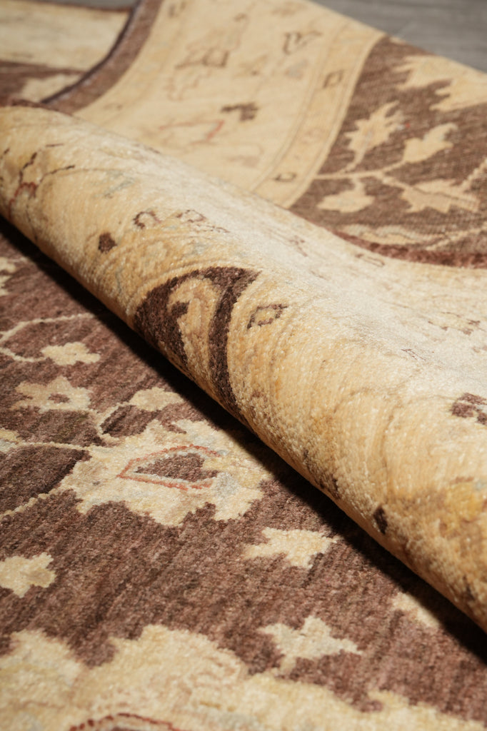Close-up of a rolled area rug showing its beige and brown floral pattern.