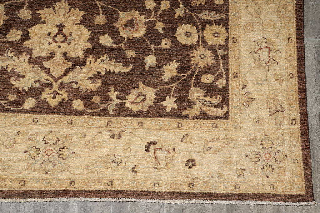 A close-up of a traditional patterned rug showing a dark brown field with beige floral motifs and a wide beige border with smaller floral details.