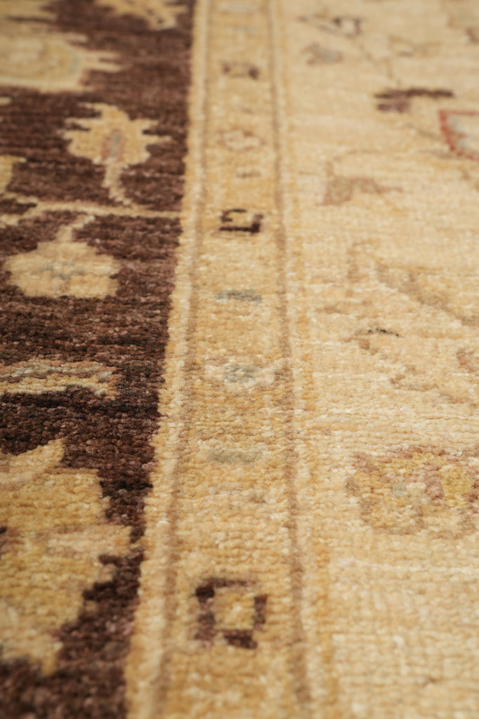 Close-up of a patterned rug showing a beige and brown woven design with a decorative border.
