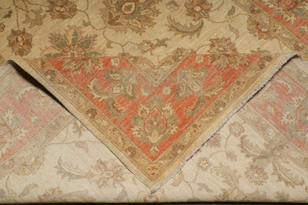 A close-up of a folded vintage-style area rug showing its intricate floral and geometric patterns in beige, rust red, and muted green.