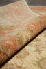 Load image into Gallery viewer, A close-up of a patterned rug with a rolled section showing its texture and design. The rug features a traditional floral or paisley motif in muted tones of beige, dusty pink, ochre, and olive green.