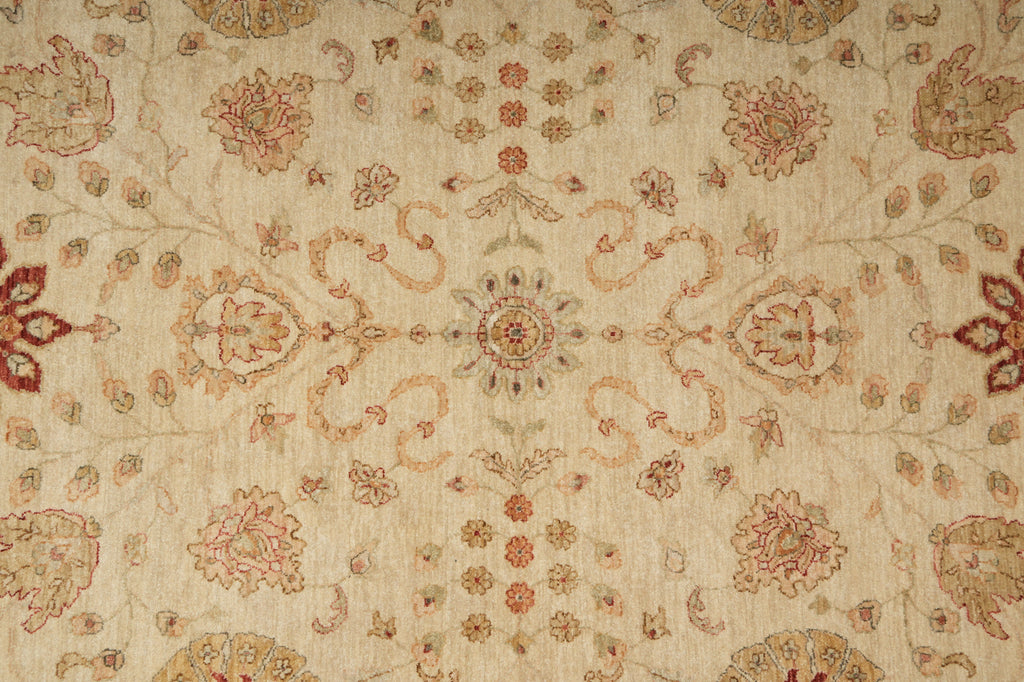 A close-up of a traditional patterned rug with a beige background and intricate floral motifs in muted red, brown, and soft green.
