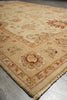 Load image into Gallery viewer, A close-up view of an ornate area rug corner, showing a cream and beige base with red and muted green floral motifs and a fringed edge on a gray floor.